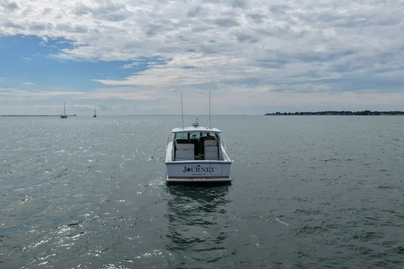 Slide: The Image of 2001 Tiara Yachts 3800 Open boat named "Journey" on calm waters under cloudy sky. - 4