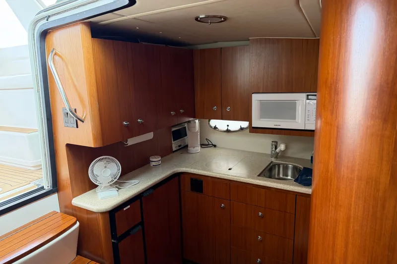 Slide: The Image of 2001 Tiara Yachts 3800 Open galley with wood cabinetry, sink, and microwave. - 6