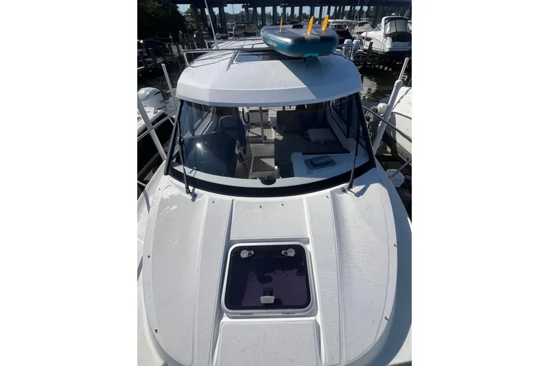 Slide: The Image of 2020 Jeanneau NC 795 boat docked, with paddleboard on roof, viewed from front. - 17