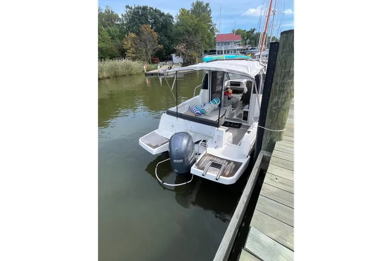 Slide: The Image of 2020 Jeanneau NC 795 boat docked, featuring outboard motor and spacious deck. - 2