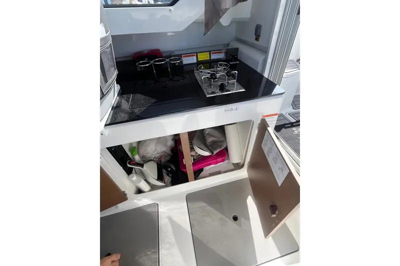 Slide: The Image of Compact kitchen area in a 2020 Jeanneau NC 795 boat, featuring a stove and storage. - 22
