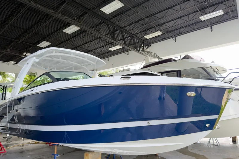 The Image of 2026 Four Winns H9 OB boat in showroom, featuring sleek blue and white design. - 1