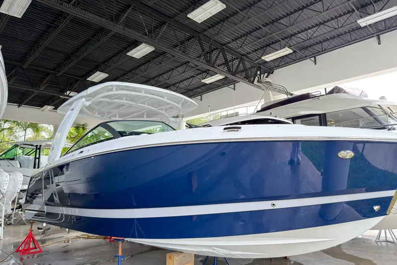 Slide: The Image of 2026 Four Winns H9 OB boat in showroom, featuring sleek blue and white design. - 2