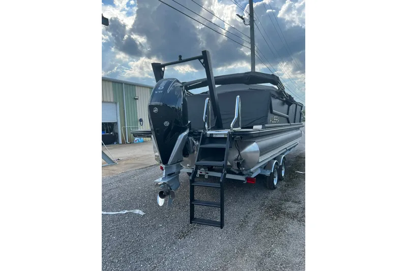 Slide: The Image of 2026 Alera M 23Q boat with powerful outboard motor, parked outdoors under cloudy sky. - 4