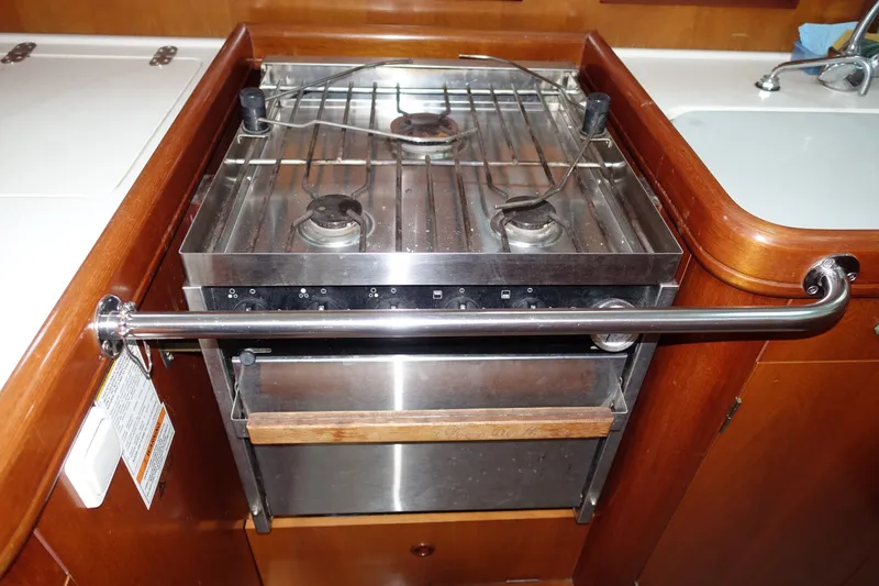 Slide: The Image of Galley stove in 2001 Beneteau Oceanis 461 yacht, featuring stainless steel burners and safety rail. - 44