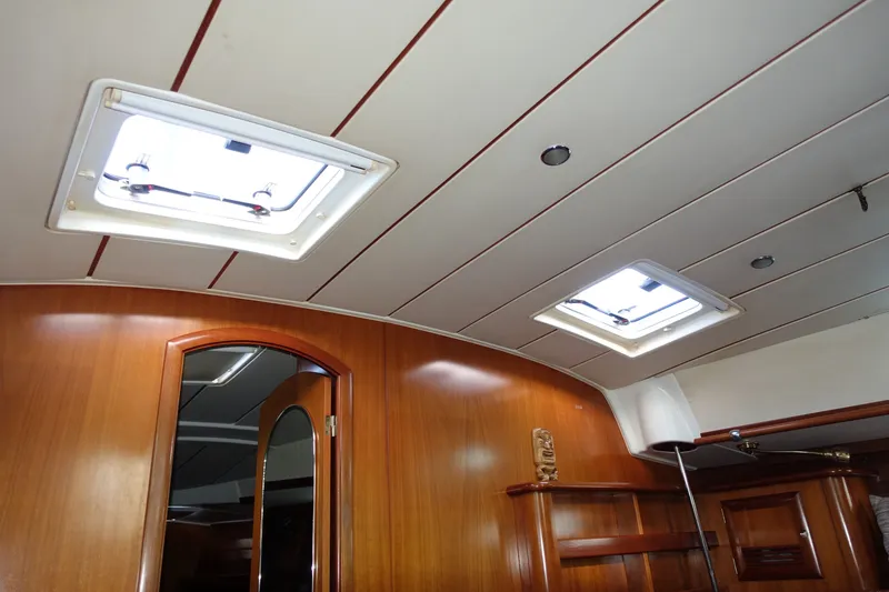 Slide: The Image of Interior view of 2001 Beneteau Oceanis 461 yacht, featuring wooden paneling and ceiling hatches. - 54