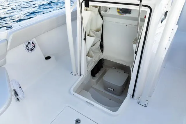 Slide: The Image of 2023 Wellcraft 222F boat interior with compact marine toilet and storage area. - 15
