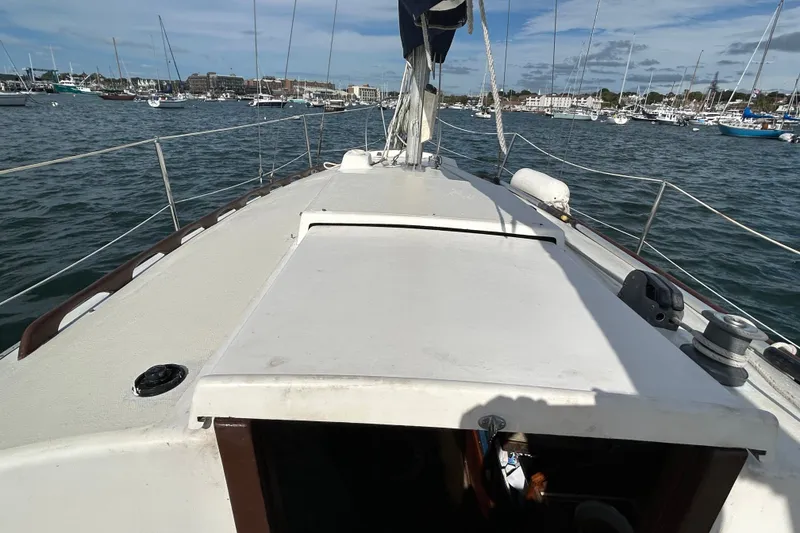 Slide: The Image of 1976 Sabre 28 sailboat deck view, moored in a bustling marina under a partly cloudy sky. - 28