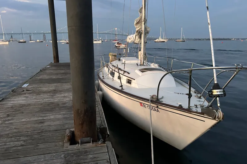 Slide: The Image of 1976 Sabre 28 sailboat docked by a wooden pier, with a scenic harbor view. - 23