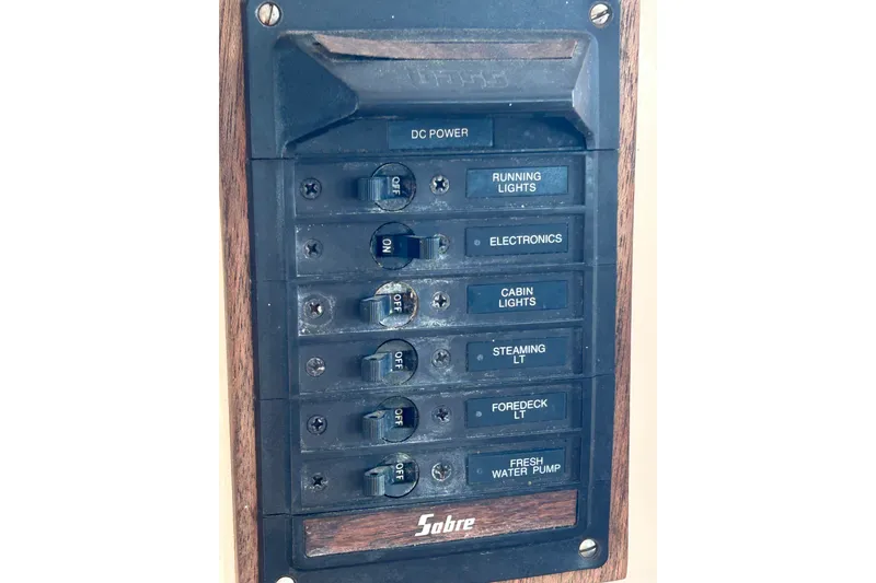 Slide: The Image of Electrical panel of a 1976 Sabre 28 sailboat with labeled switches for various functions. - 53