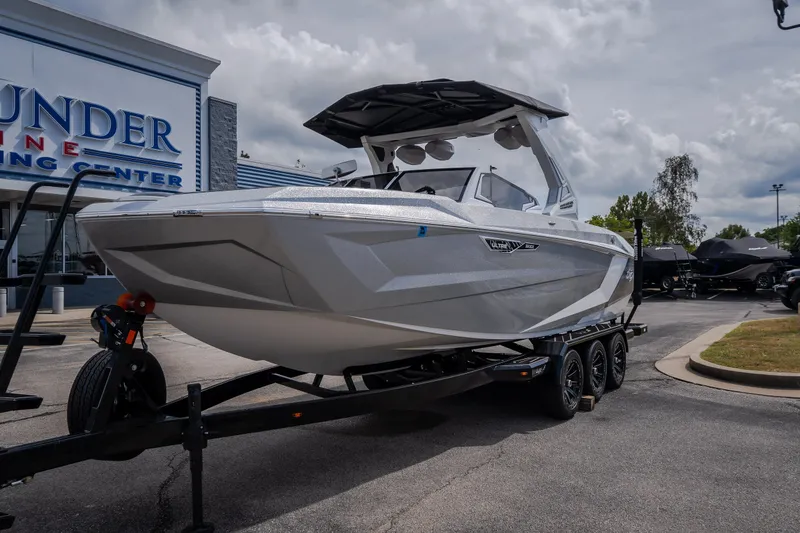 Slide: The Image of 2026 Tigé Ultré 25ZX boat on trailer at dealership, showcasing sleek design. - 2