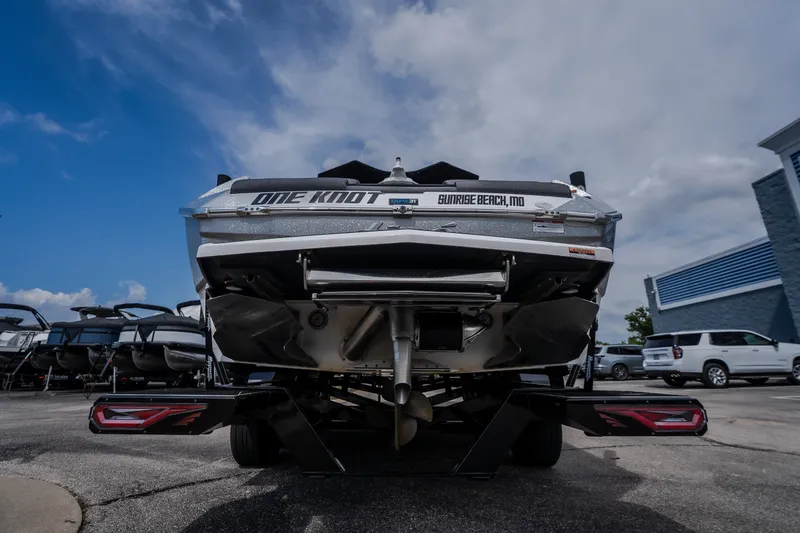Slide: The Image of 2026 Tigé Ultré 25ZX boat rear view in a parking lot under a cloudy sky. - 13
