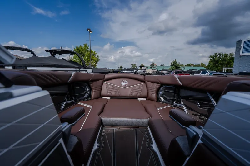 Slide: The Image of 2026 Tigé Ultré 25ZX boat interior with luxurious brown seating under a partly cloudy sky. - 49