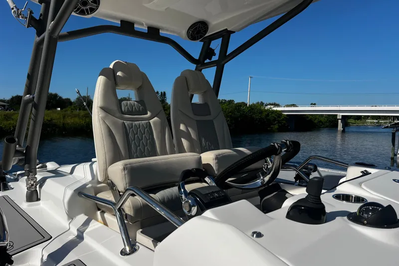 Slide: The Image of 2021 Solace 345CC boat cockpit with dual seats and steering wheel, near a bridge. - 21