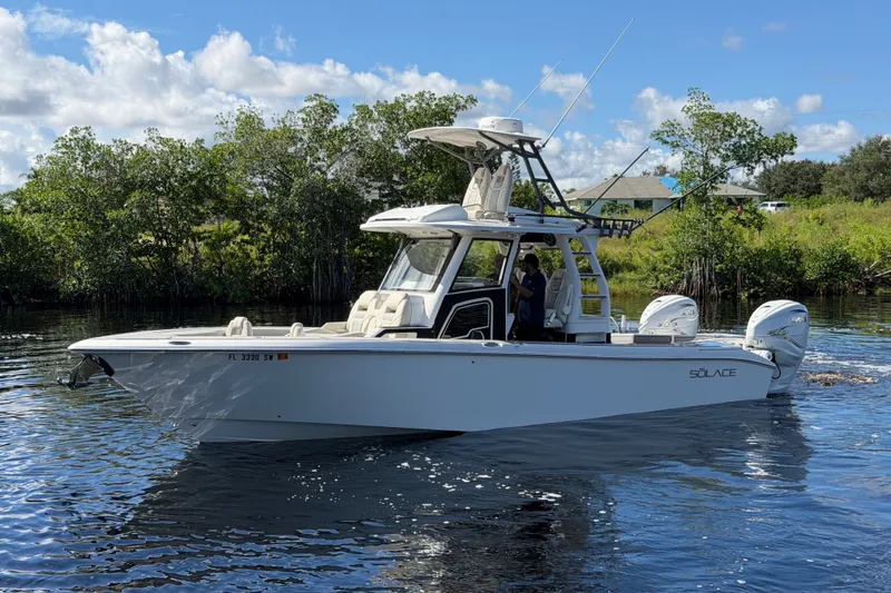 The Image of 2021 Solace 345CC boat cruising on a calm river under a clear blue sky. - 0