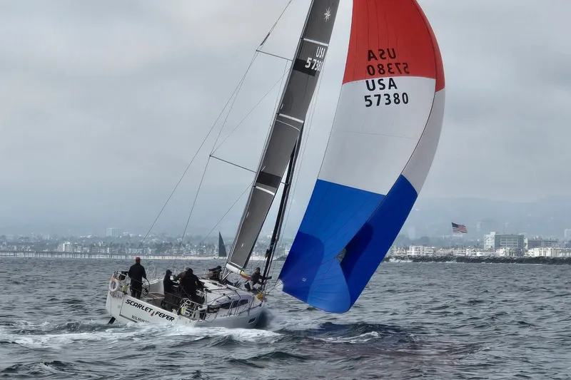 Slide: The Image of 2024 Jeanneau Sun Odyssey 380 sailing with colorful spinnaker near city skyline. - 1