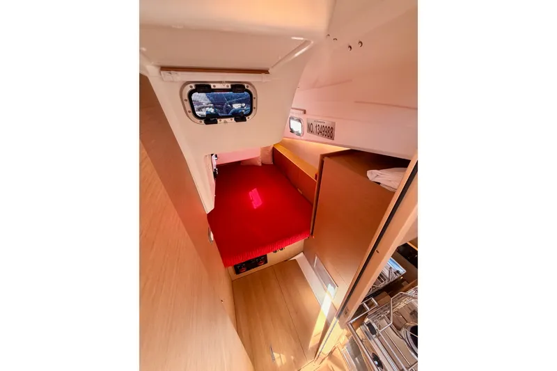 Slide: The Image of Interior cabin of 2024 Jeanneau Sun Odyssey 380 with red bedding and wooden finish. - 47