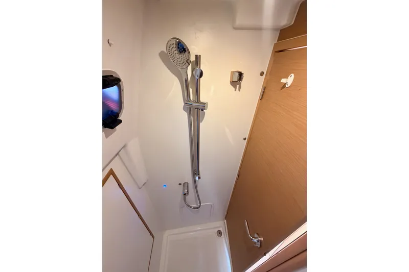 Slide: The Image of 2024 Jeanneau Sun Odyssey 380 shower area with modern fixtures and wooden door. - 55