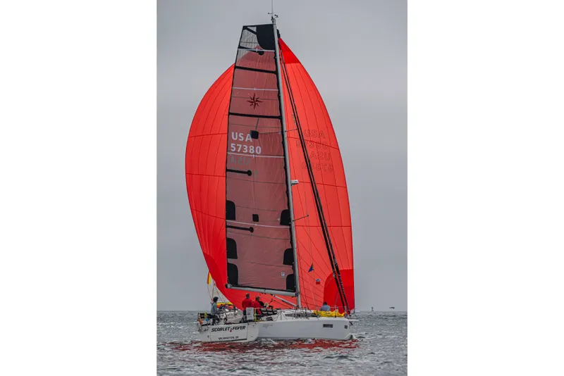 Slide: The Image of 2024 Jeanneau Sun Odyssey 380 sailing with vibrant red spinnaker on open water. - 2