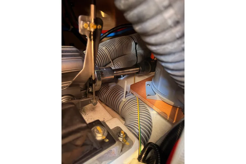 Slide: The Image of Engine compartment of 2024 Jeanneau Sun Odyssey 380 sailboat, showcasing mechanical components and hoses. - 79