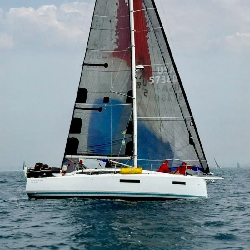 The Image of 2024 Jeanneau Sun Odyssey 380 sailing on calm waters with colorful sail and several people on board. - 0