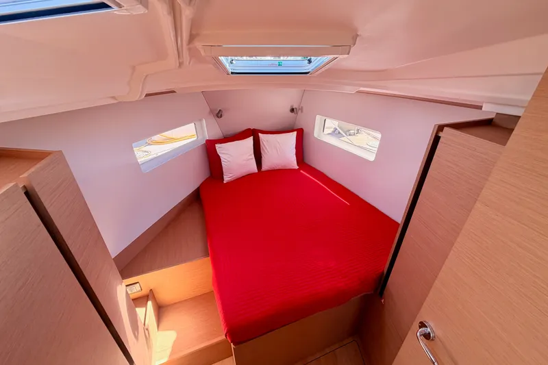 Slide: The Image of 2024 Jeanneau Sun Odyssey 380 cabin with red bedding and natural light. - 67