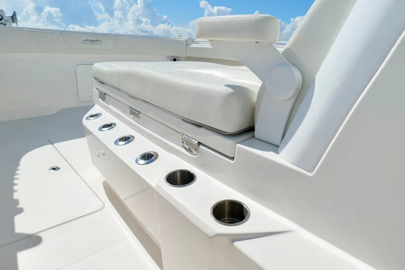 Slide: The Image of 2022 Invincible 33 Catamaran interior with white seating and cup holders under a blue sky. - 36