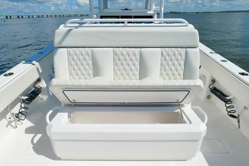 Slide: The Image of 2022 Invincible 33 Catamaran with open storage compartment, white seating, and ocean backdrop. - 24