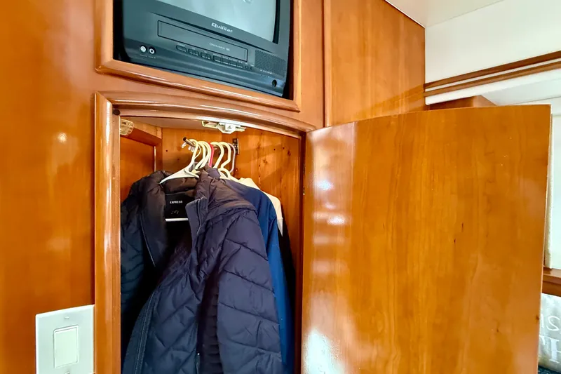 Slide: The Image of Wooden closet with jackets and a TV inside a 2000 Carver 53 Voyager yacht. - 37
