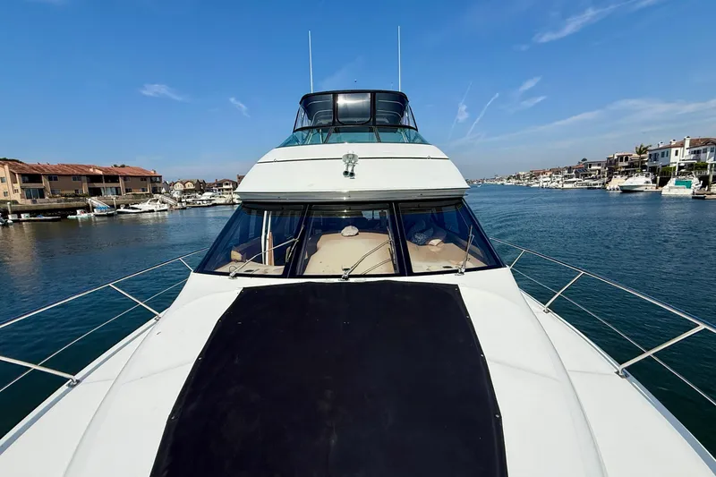 Slide: The Image of 2000 Carver 53 Voyager yacht cruising in a scenic waterfront setting. - 89
