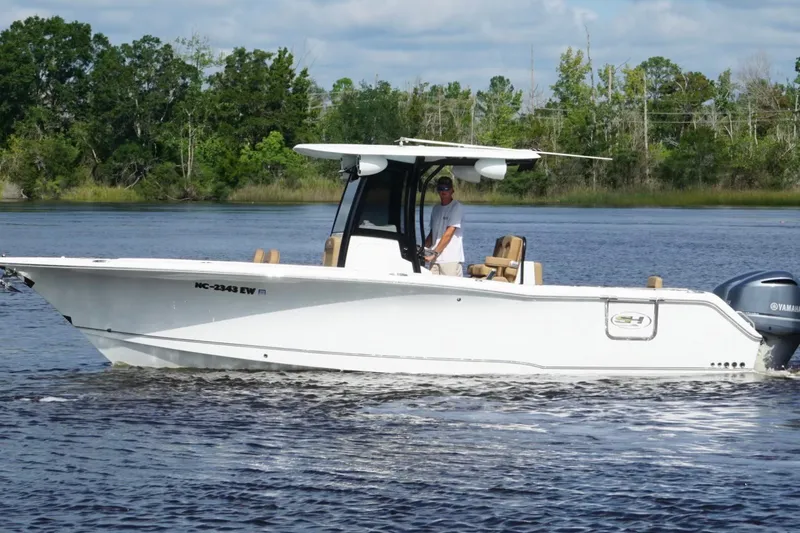 Slide: The Image of 2021 Sea Hunt Gamefish 27FS boat cruising on a calm river with lush greenery. - 5