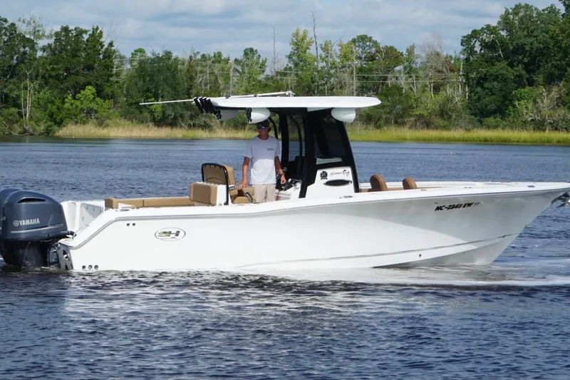 Slide: The Image of 2021 Sea Hunt Gamefish 27FS boat cruising on a calm lake with lush greenery. - 4