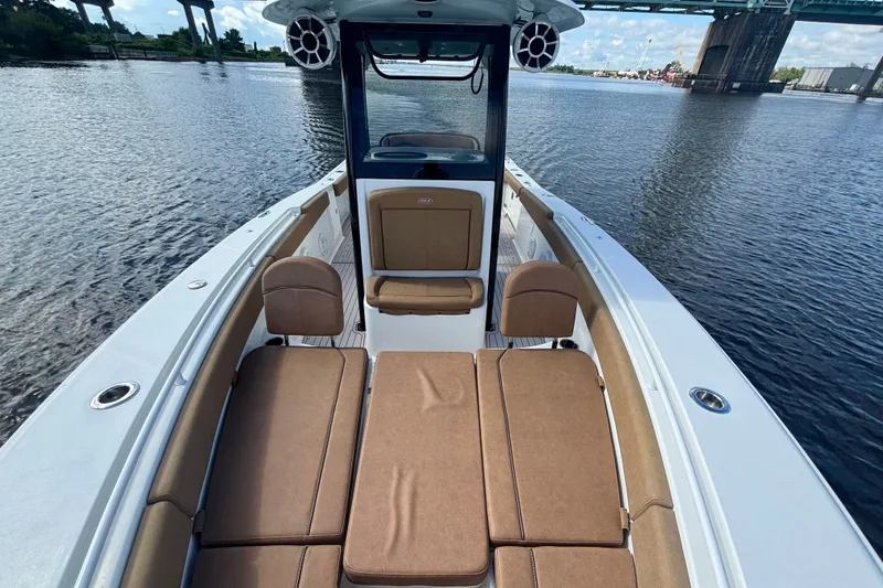 Slide: The Image of 2021 Sea Hunt Gamefish 27FS boat interior with cushioned seating on calm water. - 14