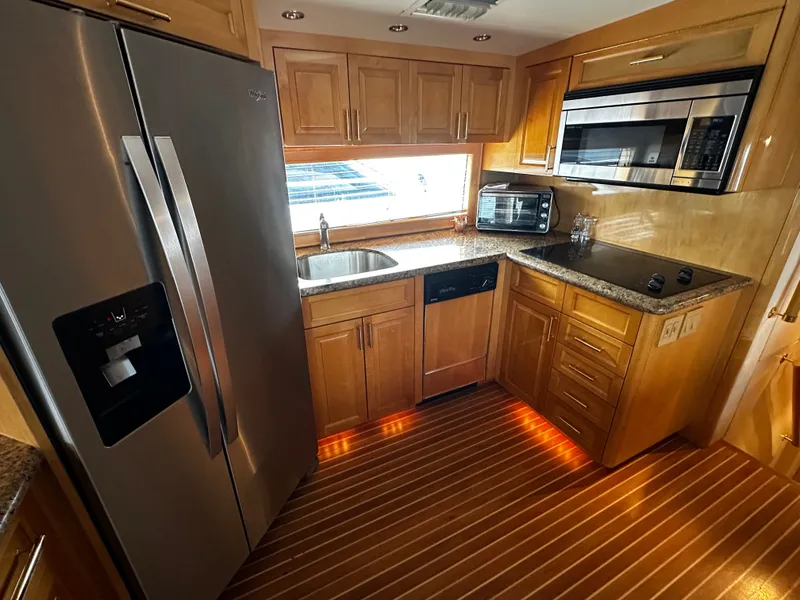 Slide: The Image of The 2000 Hatteras 70 Convertible's kitchen features modern appliances and wooden cabinetry. - 12