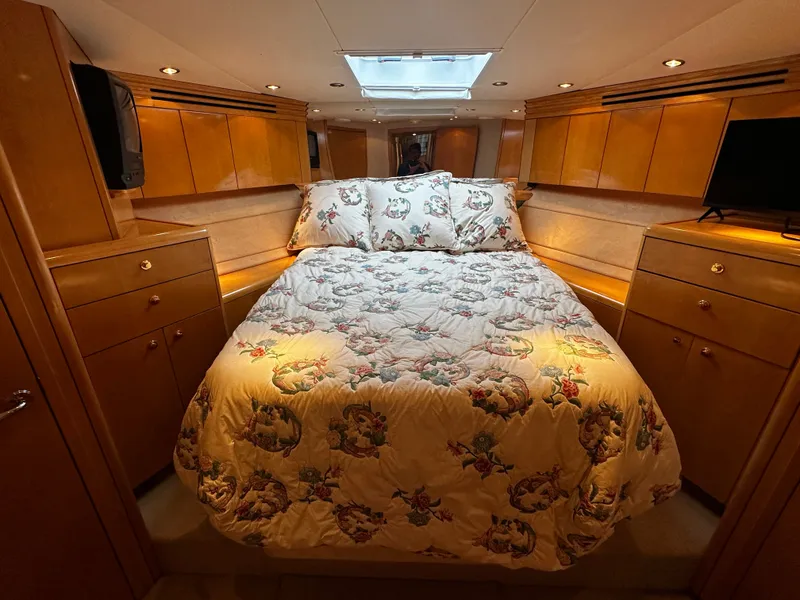 Slide: The Image of The cabin of the 2000 Hatteras 70 Convertible features a cozy bed with a floral bedspread. - 24