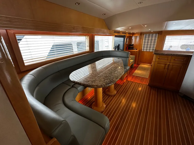 Slide: The Image of Interior of a 2000 Hatteras 70 Convertible with curved seating and a marble table. - 10