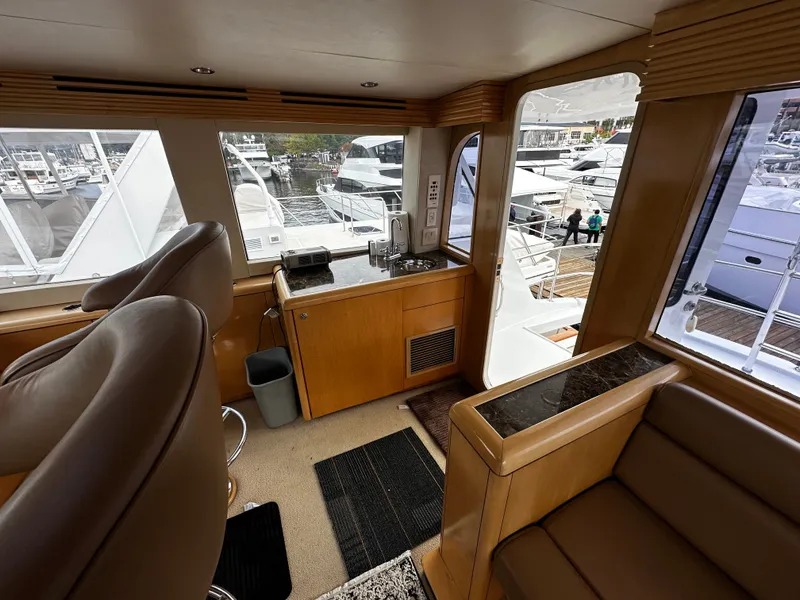 Slide: The Image of Interior of a 2000 Hatteras 70 Convertible with leather seating and wood furnishings, overlooking a marina. - 42