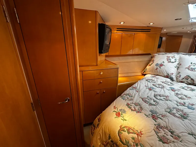Slide: The Image of The cabin of a 2000 Hatteras 70 Convertible with wooden furnishings and a cozy bed. - 25