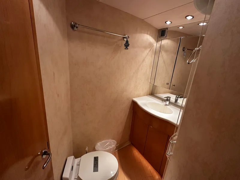 Slide: The Image of Bathroom with wood paneling, sink, mirror, and toilet in a Hatteras 70 Convertible yacht. - 23
