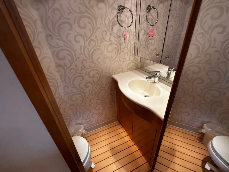 Slide: The Image of An elegant bathroom with wood flooring and a curved sink in a Hatteras 70 Convertible. - 26