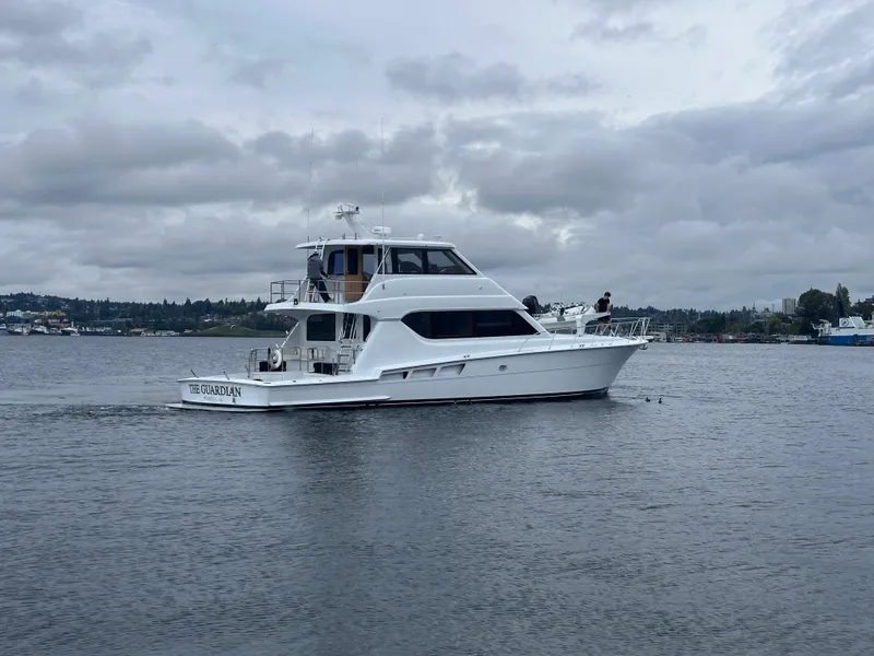 Slide: The Image of A 2000 Hatteras 70 Convertible yacht on calm water under a cloudy sky. - 4
