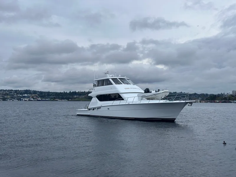 Slide: The Image of A 2000 Hatteras 70 Convertible on calm water under a cloudy sky. - 1