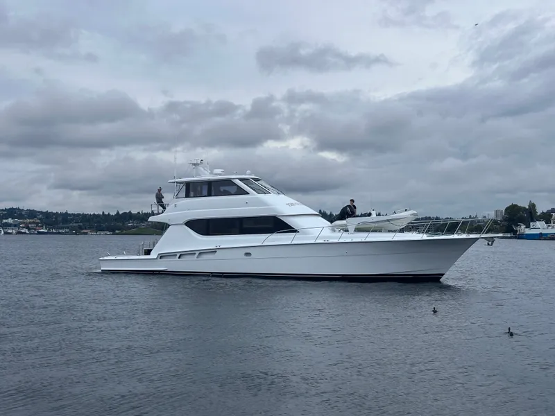 Slide: The Image of A 2000 Hatteras 70 Convertible on calm water under a cloudy sky. - 2