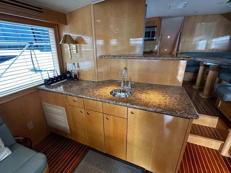 Slide: The Image of Interior of the 2000 Hatteras 70 Convertible featuring a sleek kitchen and wood finishes. - 7