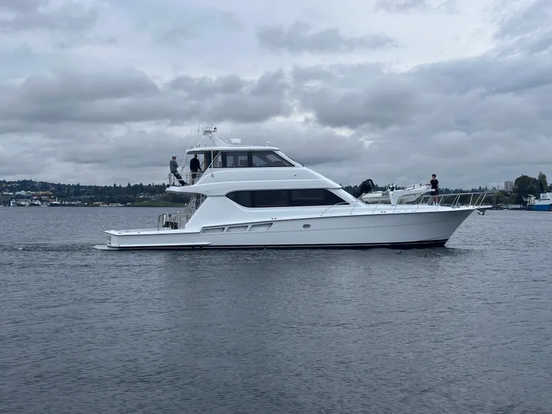 Slide: The Image of 2000 Hatteras 70 Convertible on calm water, with two people on board, cloudy sky. - 3