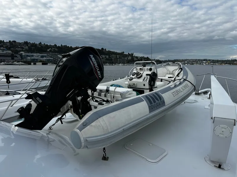 Slide: The Image of An inflatable boat with an outboard motor on a larger boat, set against a cloudy cityscape. - 44