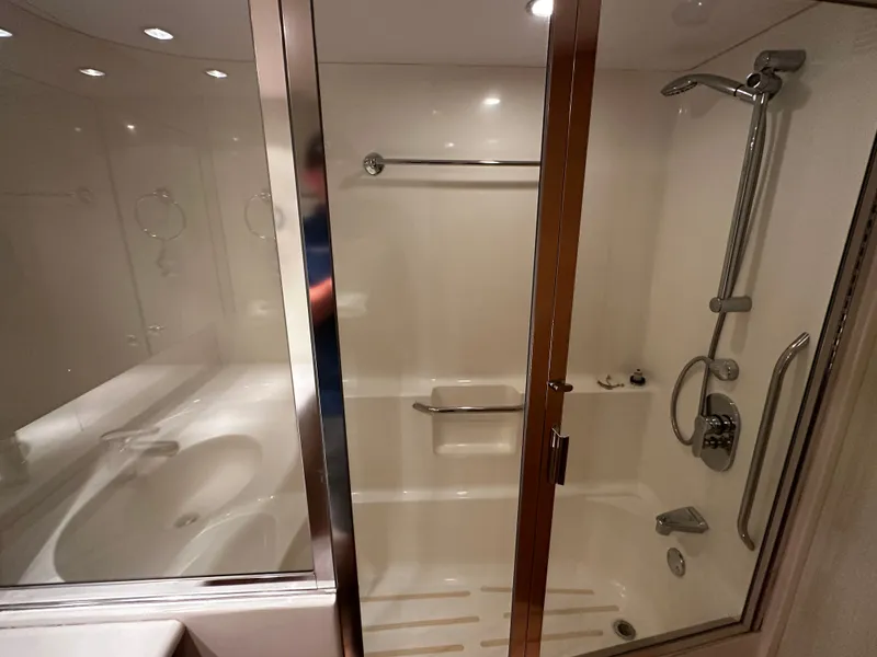 Slide: The Image of The image shows a luxurious shower cabin with glass walls and modern fixtures on a Hatteras 70 Convertible yacht. - 21