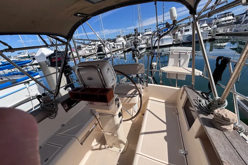 Slide: The Image of Cockpit of 2000 Island Packet 380 sailboat docked at marina, showcasing steering wheel and seating. - 43