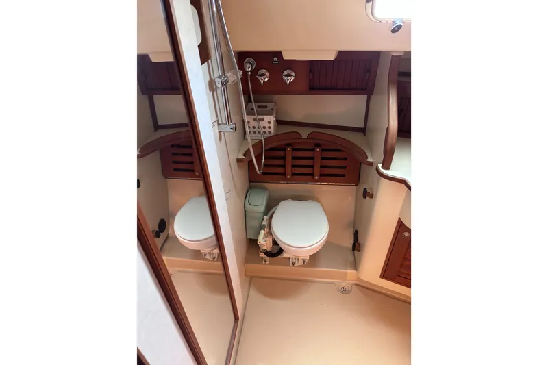 Slide: The Image of Bathroom interior of 2000 Island Packet 380 sailboat, featuring toilet and wooden cabinetry. - 28