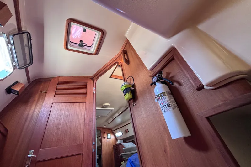 Slide: The Image of Interior of 2000 Island Packet 380 sailboat with wooden cabinetry and safety equipment. - 38